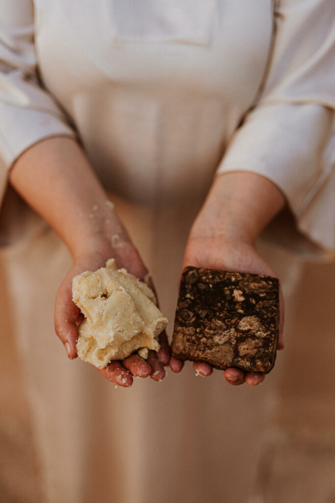 Bild på händer som håller fram oraffinerat sheasmör och blacksoap